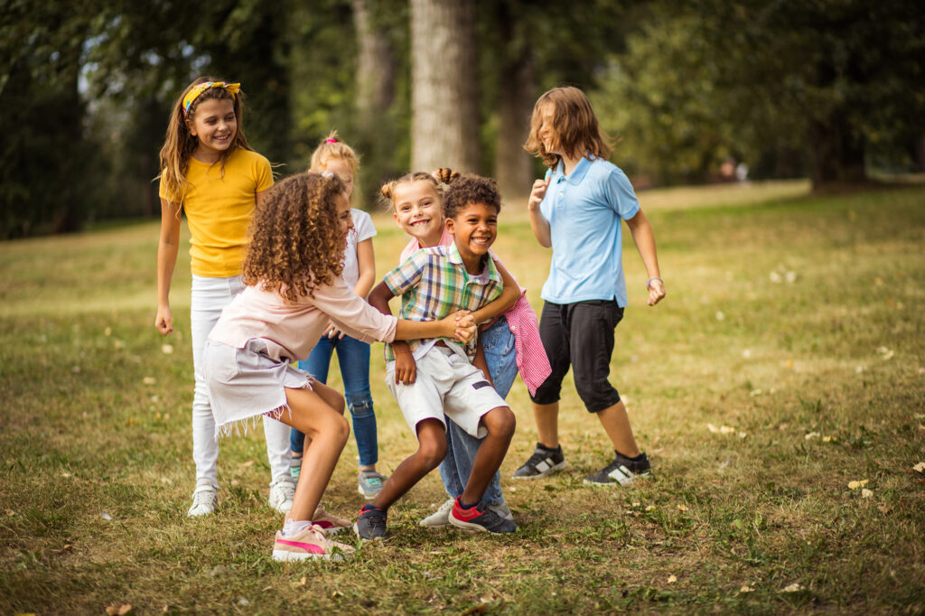 En grupp barn som leker på en gräsmatta och ler stort.